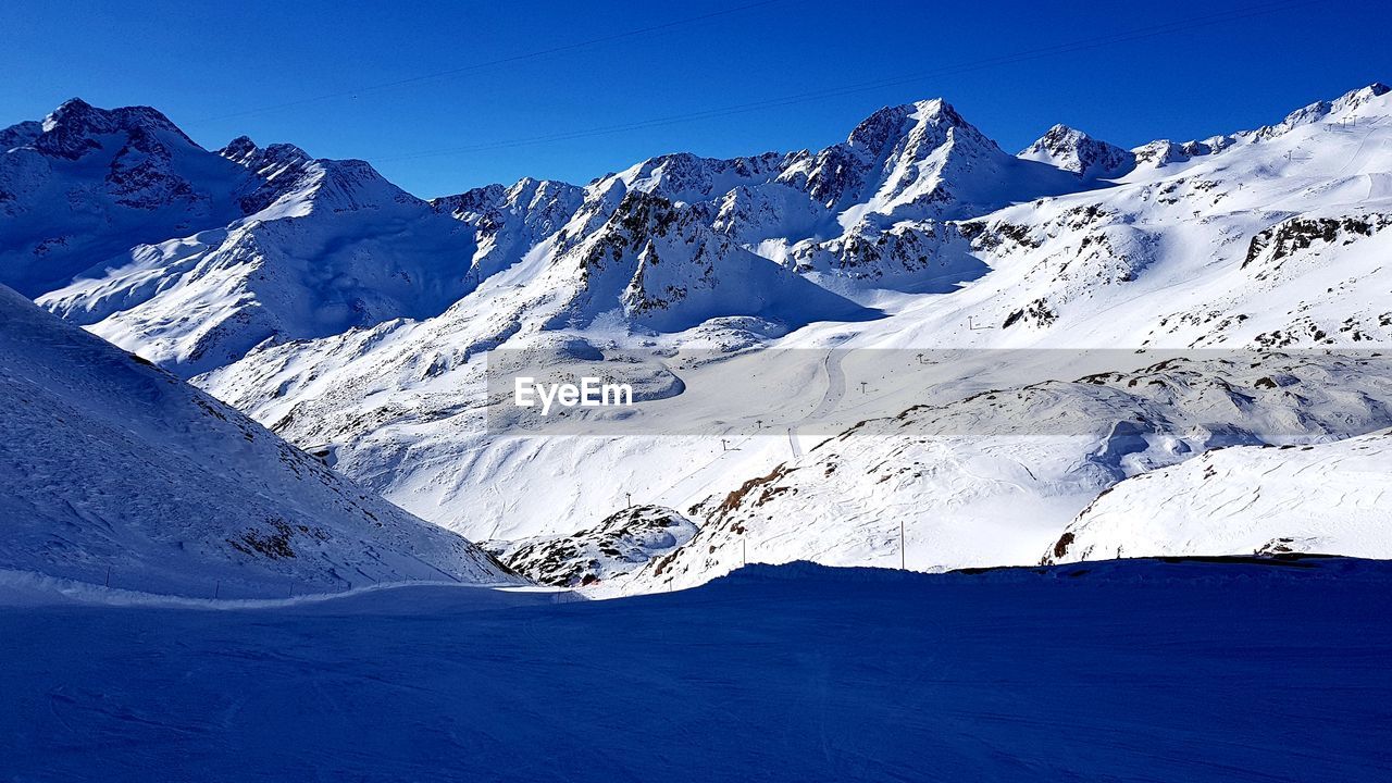 Scenic view of snowcapped mountains against clear blue sky