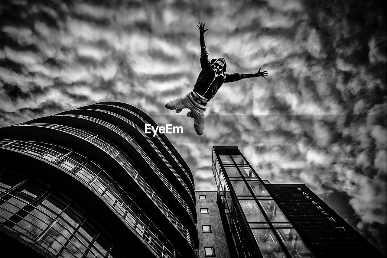 LOW ANGLE VIEW OF SKYSCRAPER AGAINST CLOUDY SKY