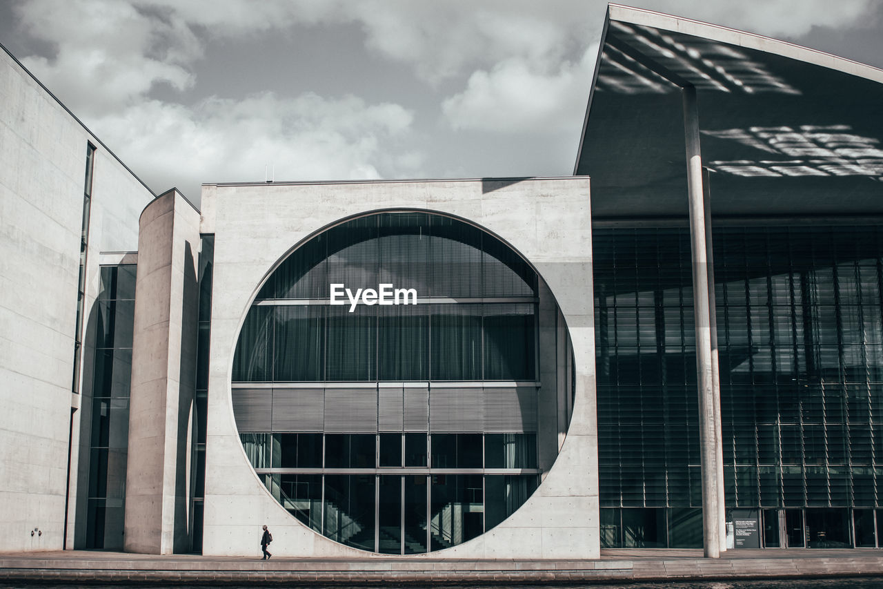 Person walking by building against sky