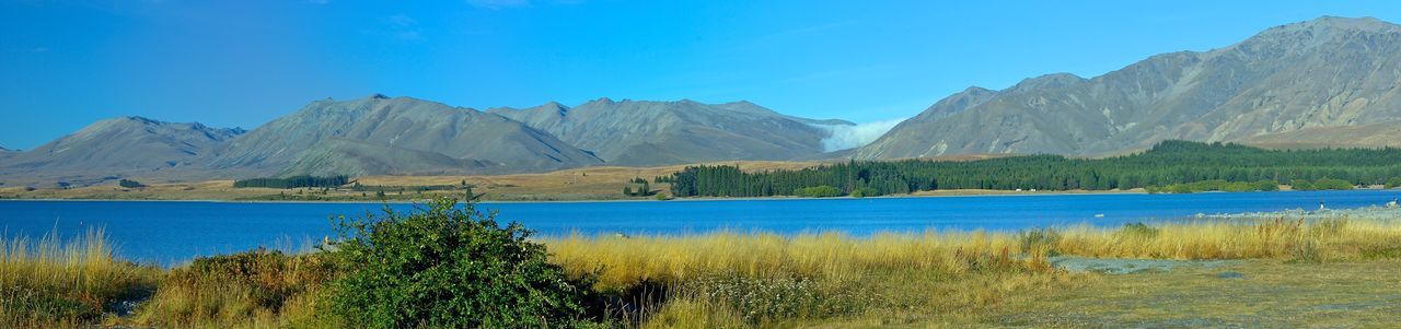 Scenic view of lake and mountains against clear blue sky