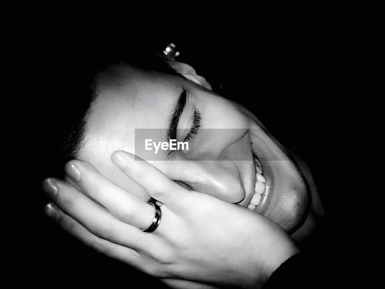 Close-up of smiling man wearing ring against black background