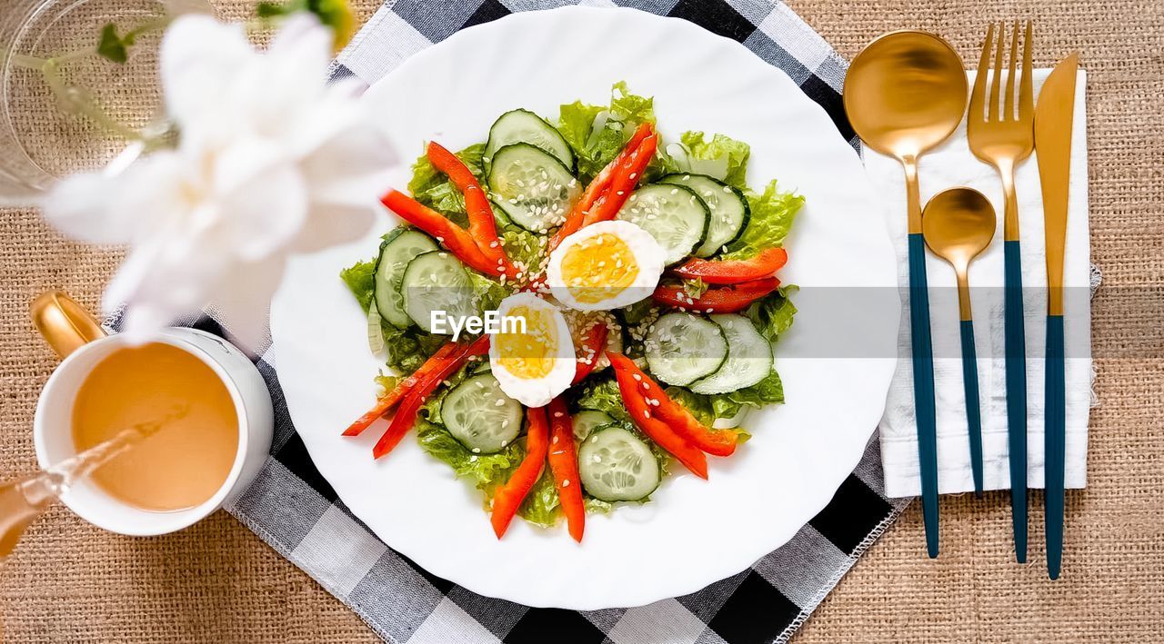 Fresh salad of herbs, cucumbers, bell pepper and boiled eggs in a plate on the table
