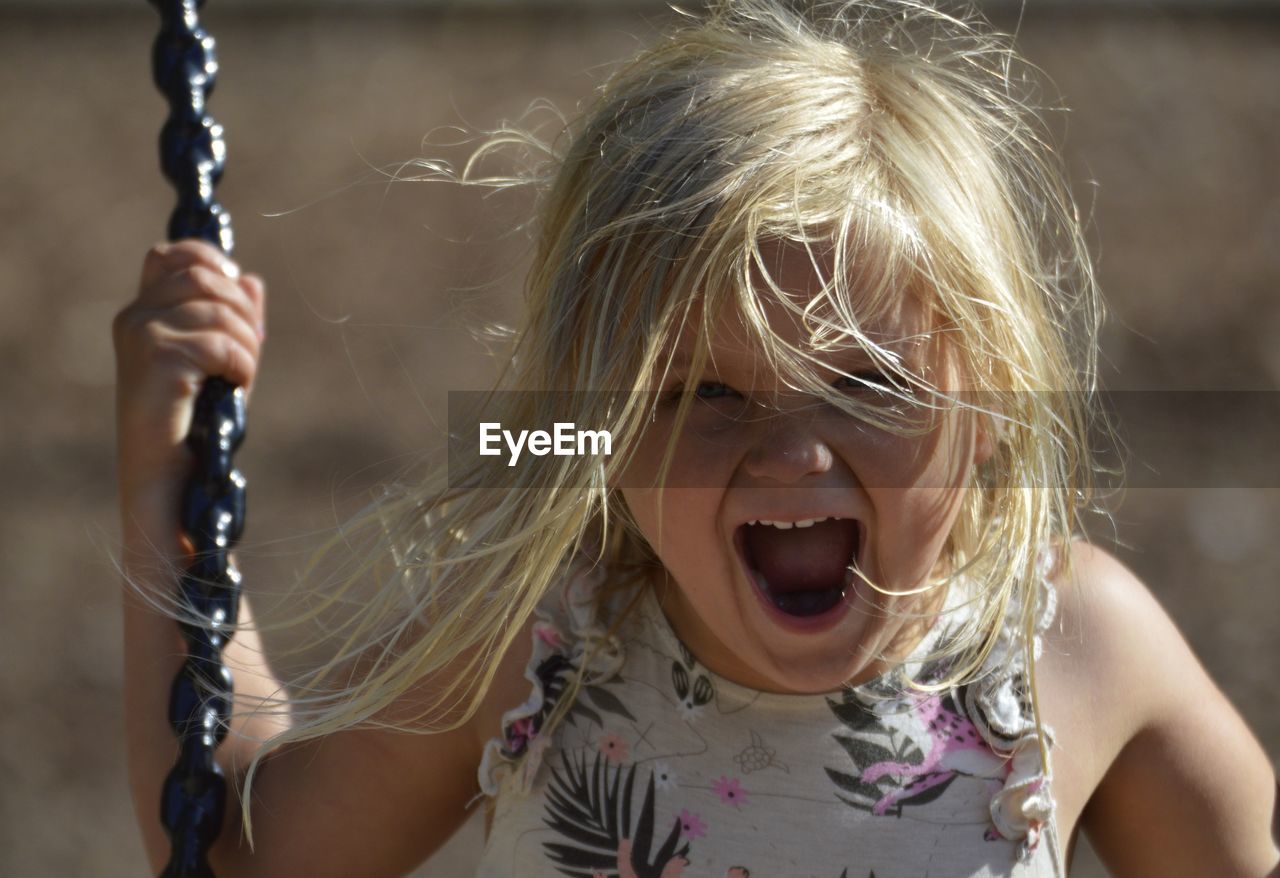 Portrait of cheerful girl on swing