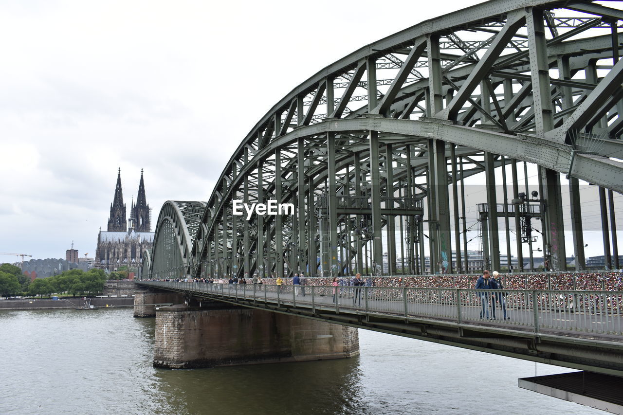 BRIDGE OVER RIVER BY BUILDINGS AGAINST SKY