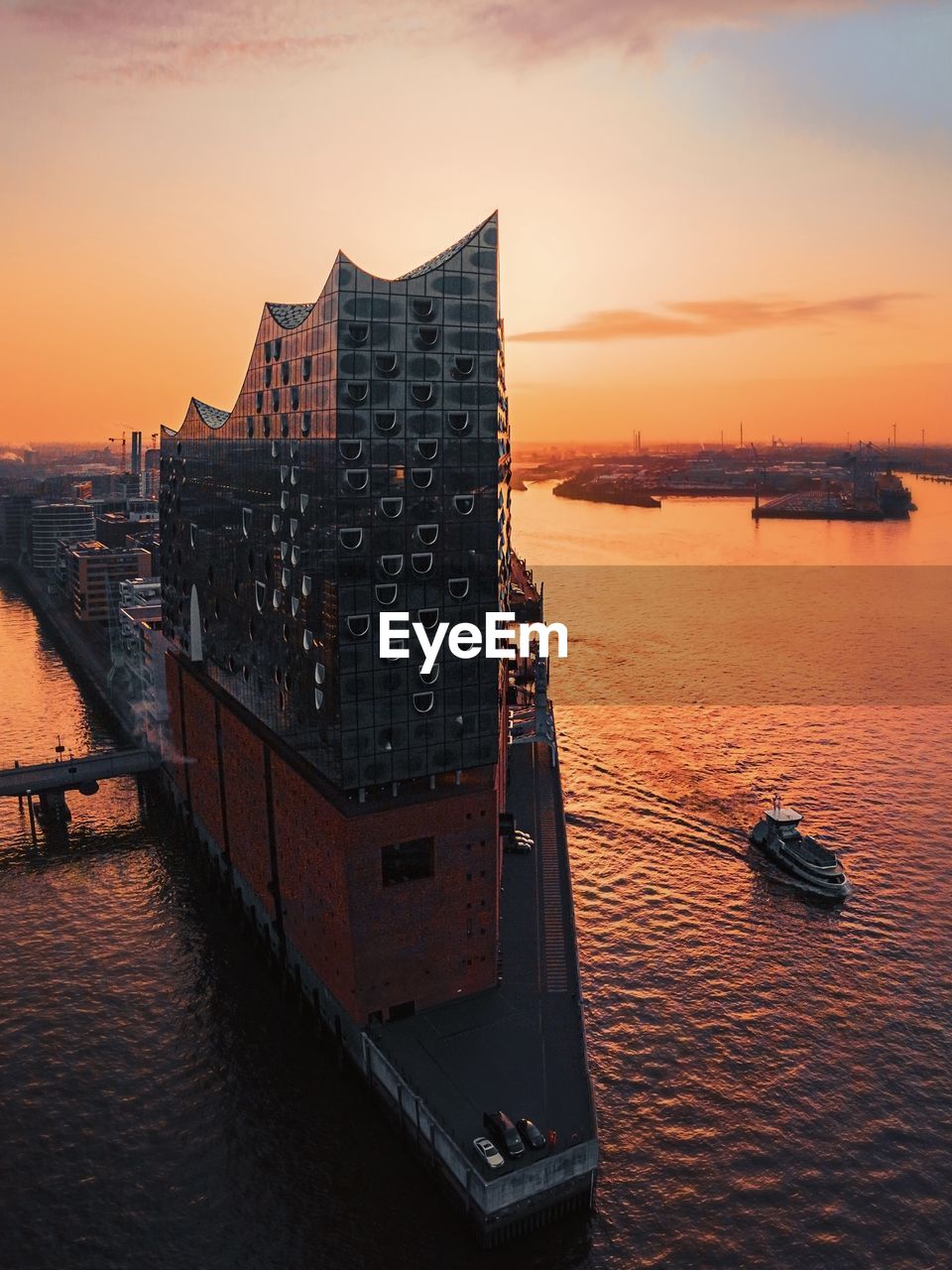 Buildings by sea against sky during sunset