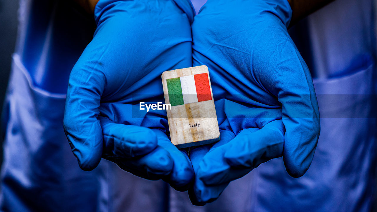 Midsection of doctor holding wood with italian flag