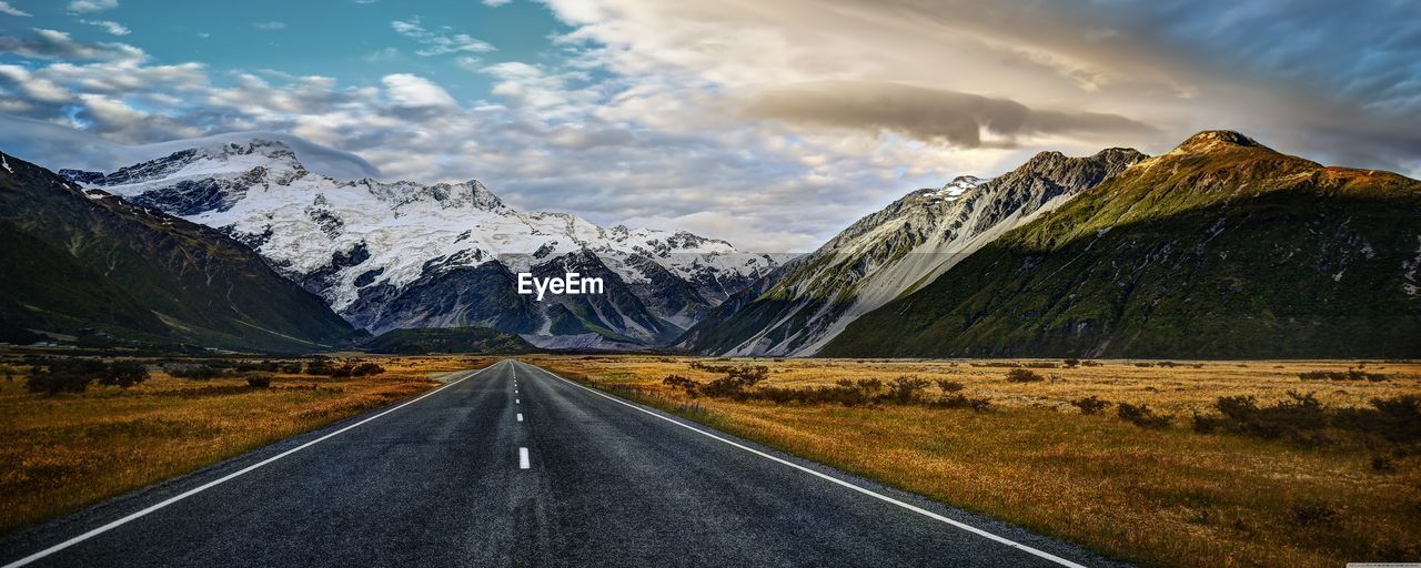 Empty road leading towards mountain against sky