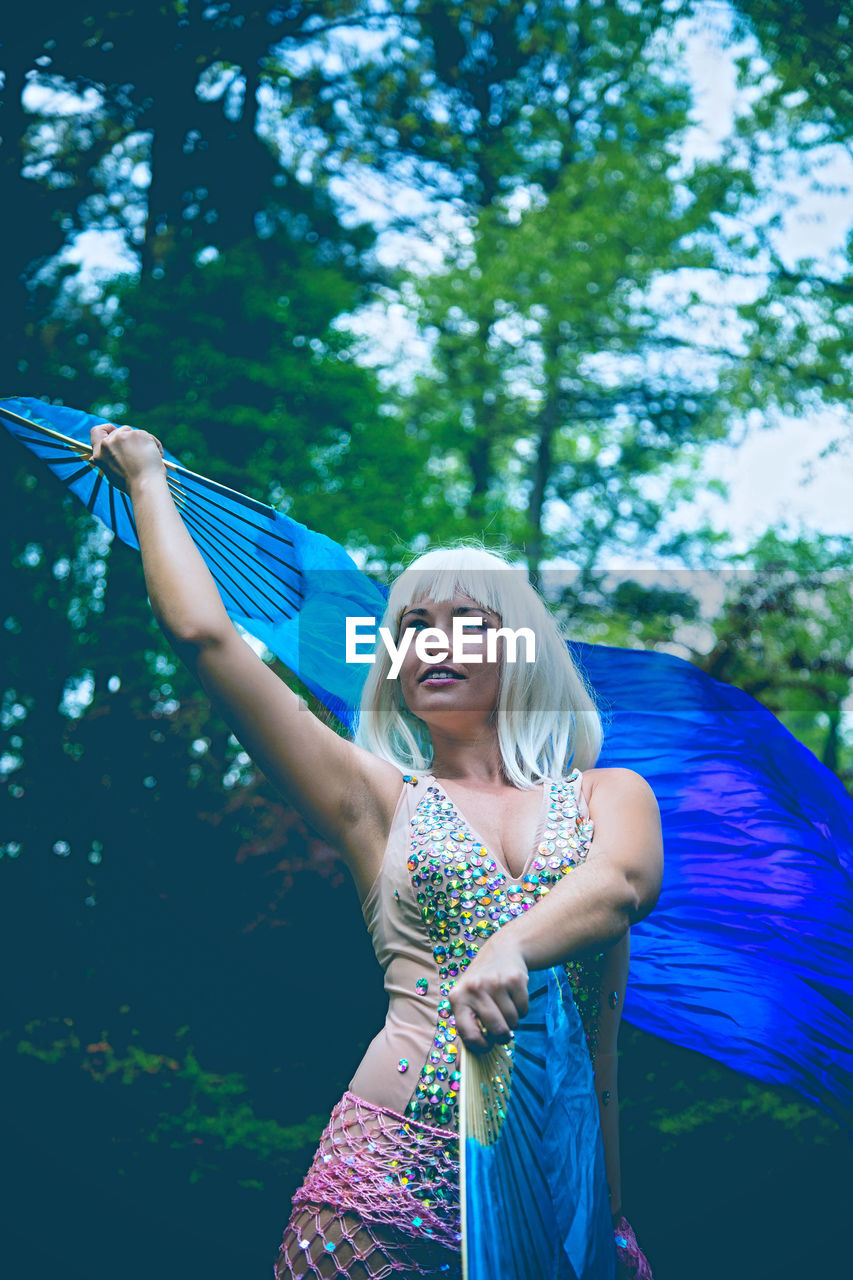 Woman with blue hand fan posing in forest