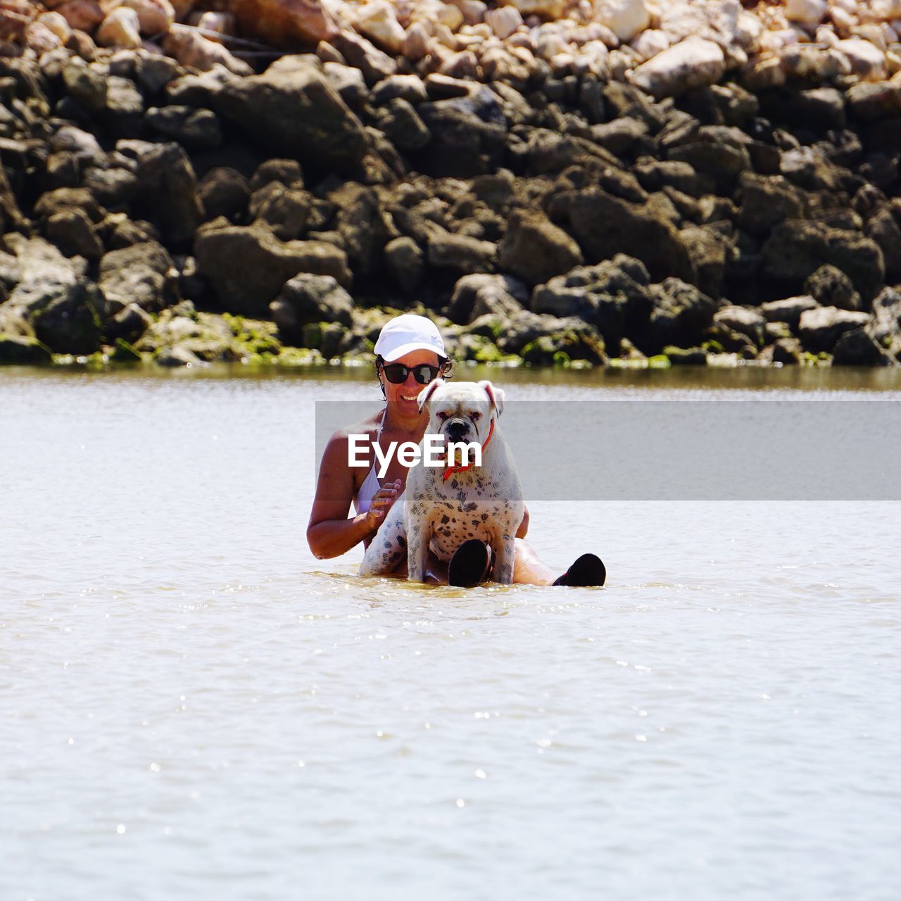 Woman sitting in lake with dog