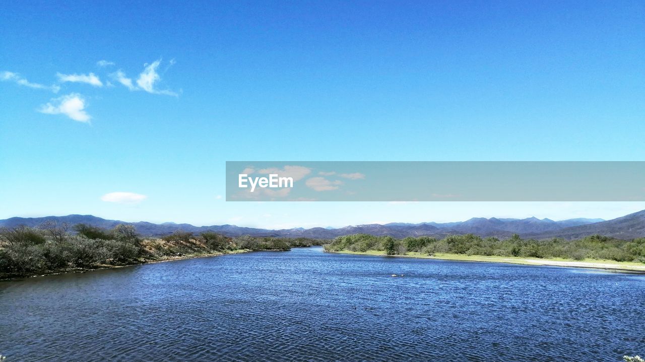 SCENIC VIEW OF LAKE AND MOUNTAINS AGAINST BLUE SKY