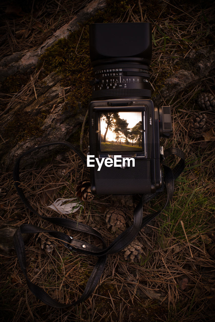 TILT IMAGE OF CAMERA PHOTOGRAPHING ON FIELD