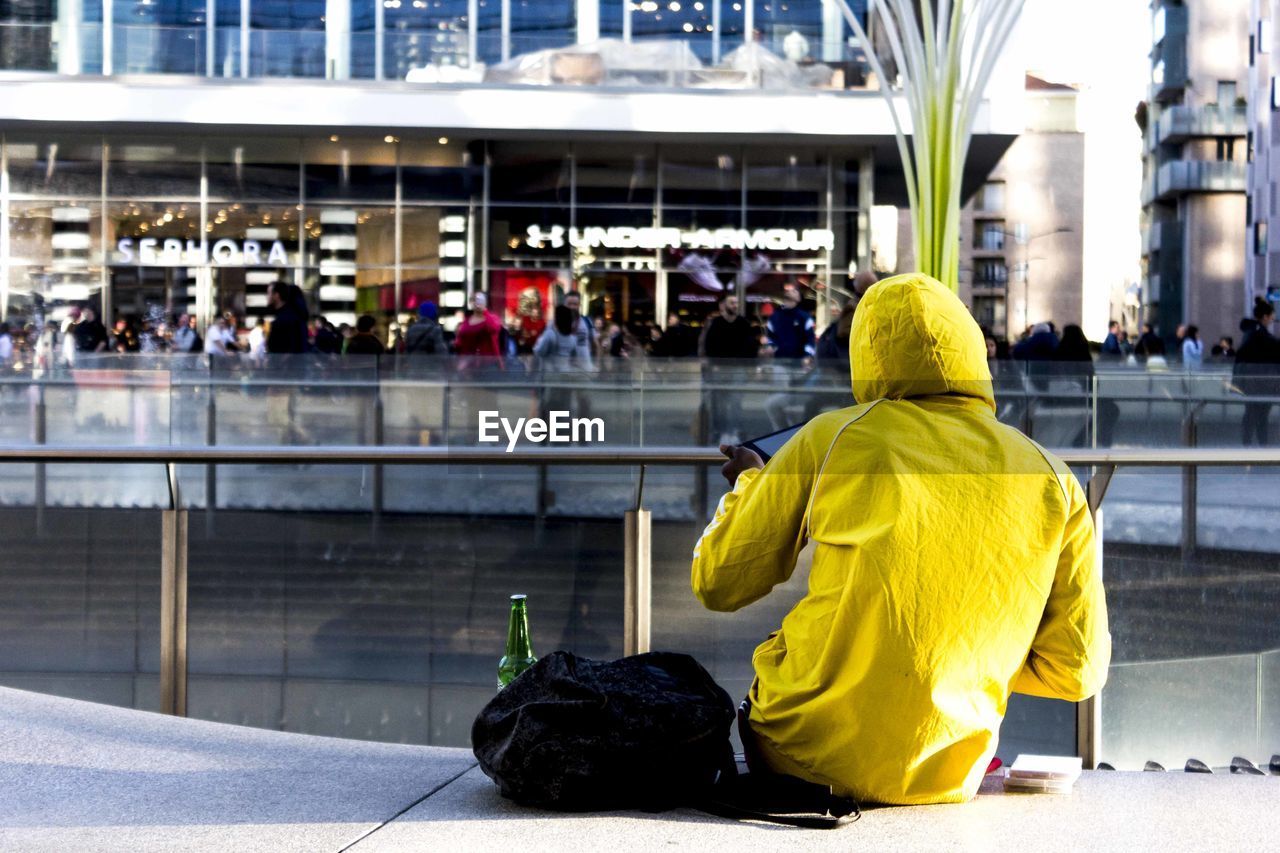 REAR VIEW OF WOMAN SITTING WITH YELLOW BELL