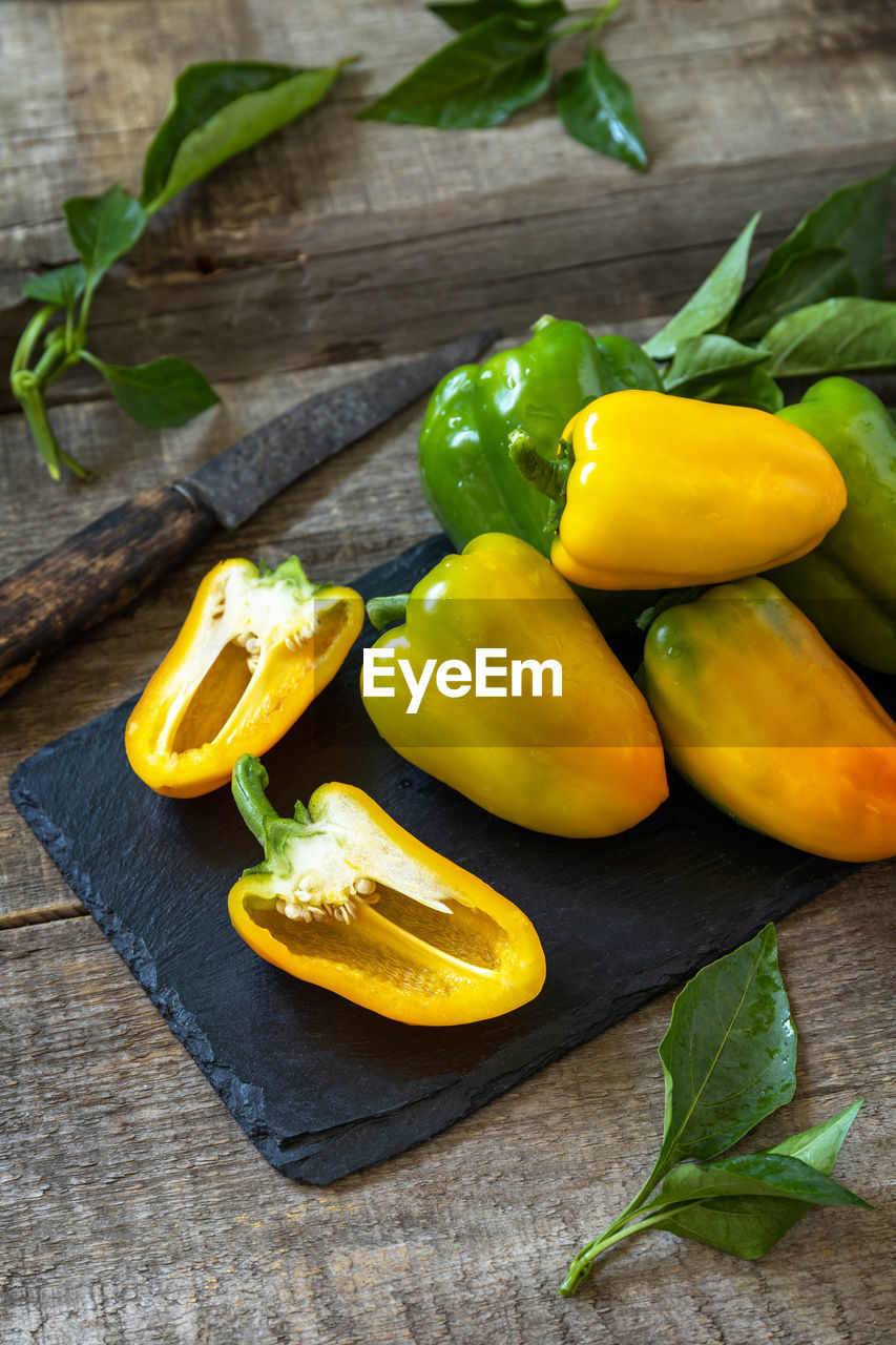 Organic healthy raw ripe sweet pepper, yellow paprika, on a kitchen wooden table. 