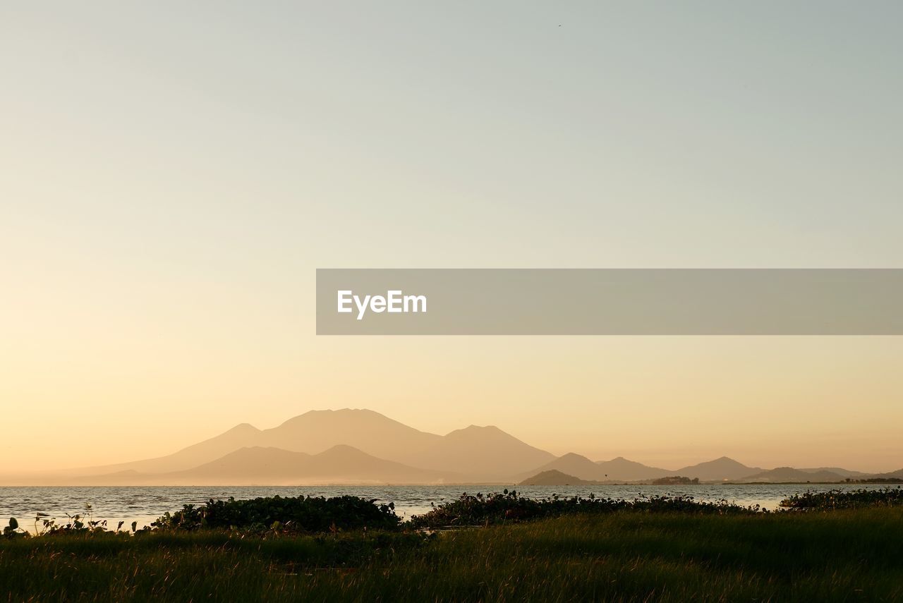 Scenic view of lake against clear sky during sunset