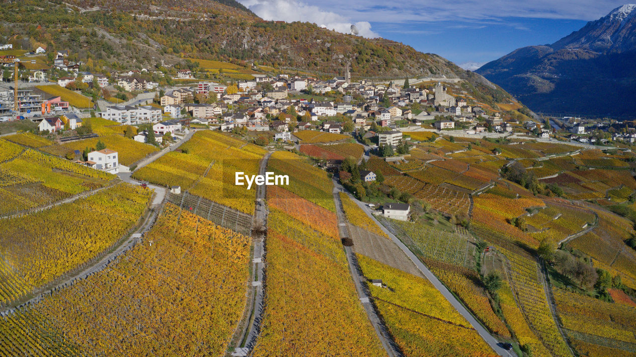 High angle view of field by buildings against mountains