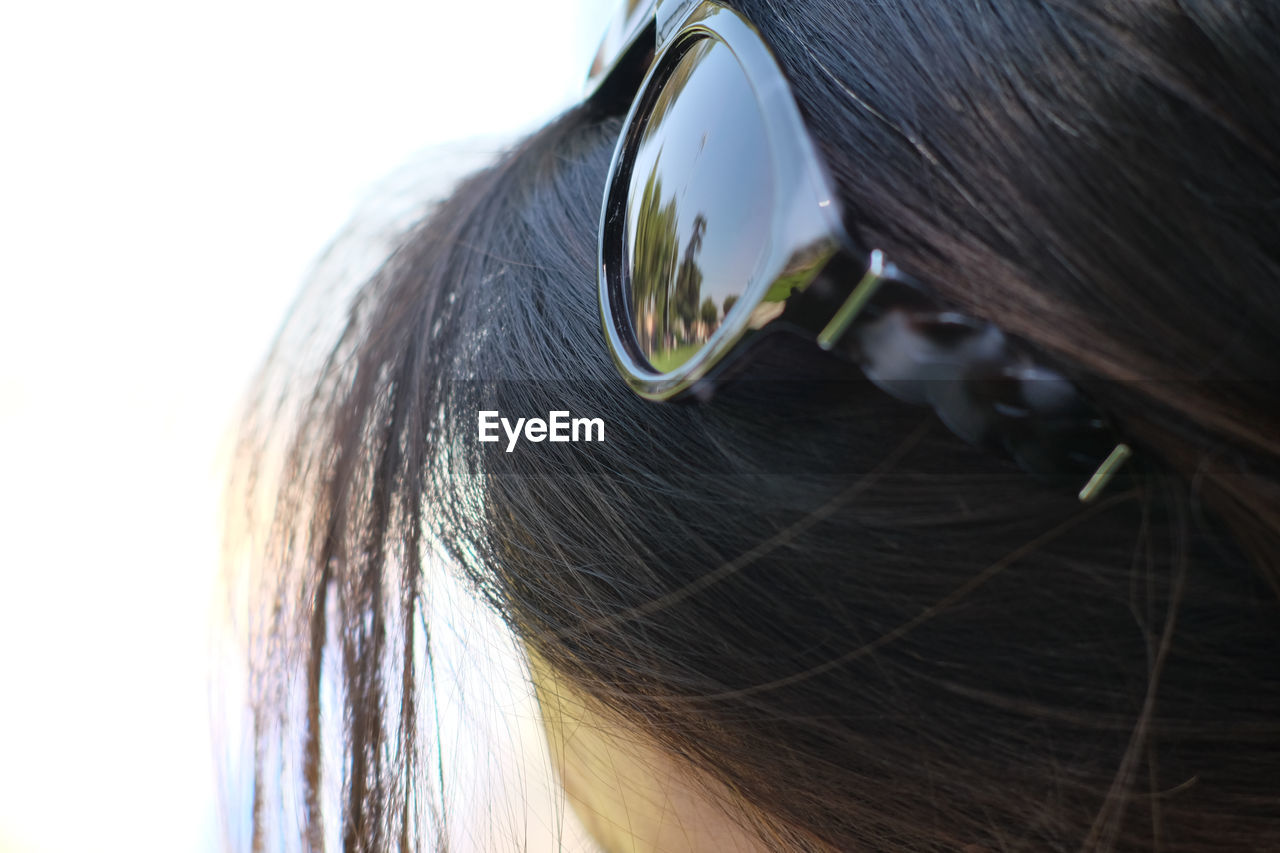 CLOSE-UP OF WOMAN WITH SUNGLASSES AGAINST BLURRED BACKGROUND