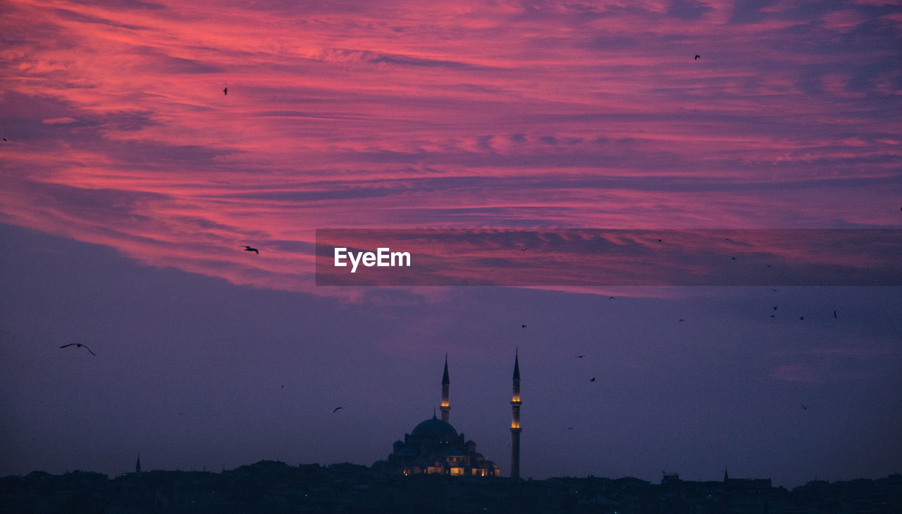 Silhouette mosque against cloudy sky during sunset