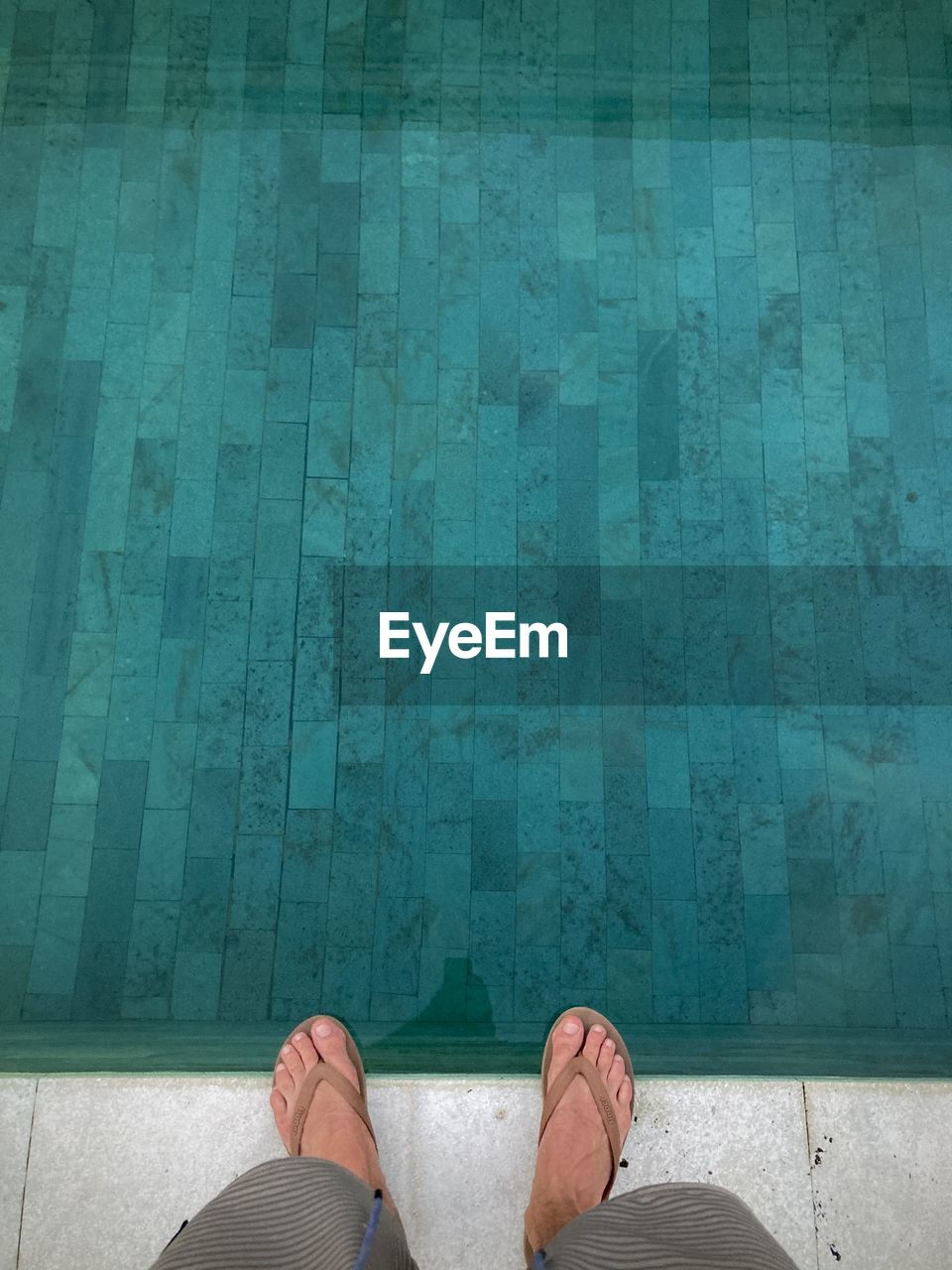 LOW SECTION OF MAN STANDING ON SWIMMING POOL