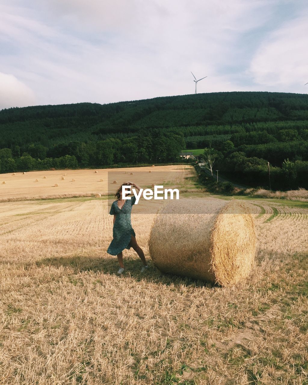 Woman standing by hay on field