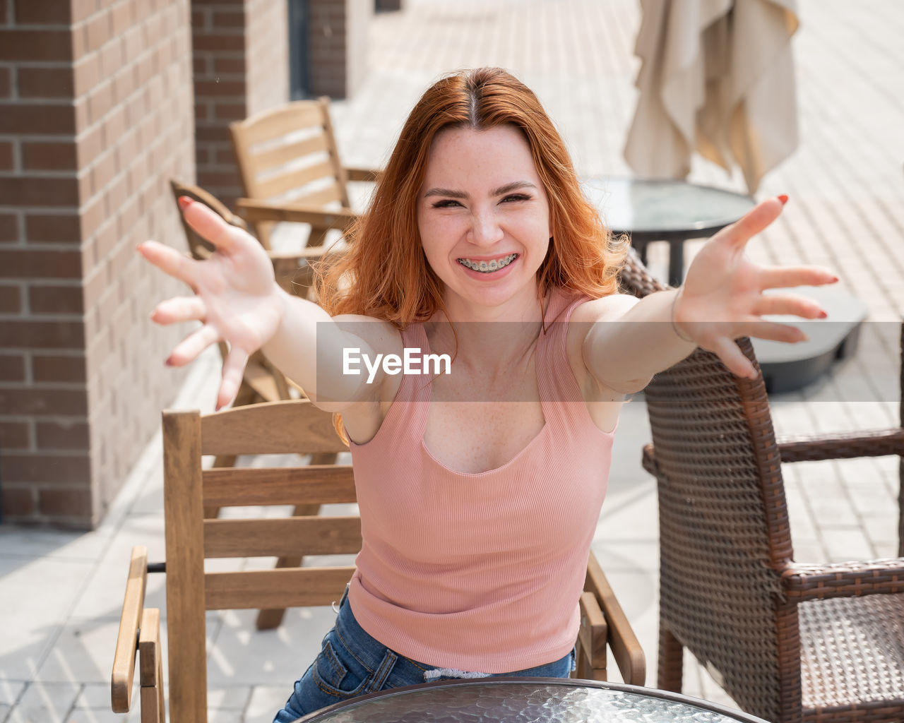 portrait of smiling young woman sitting on railing