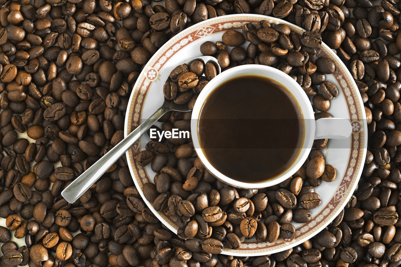 High angle view of coffee cup on roasted beans