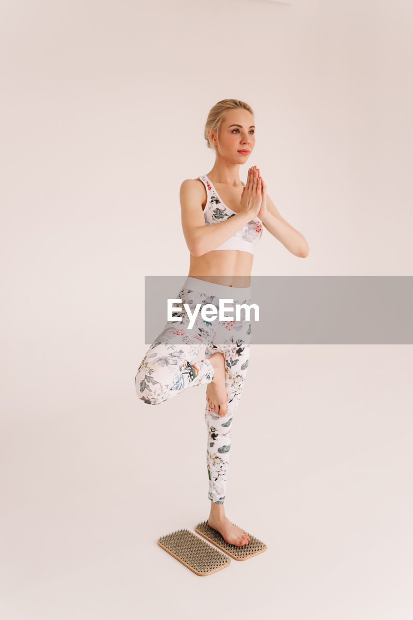 Fitness a woman in sportswear does sports yoga and physical training on a white isolated background