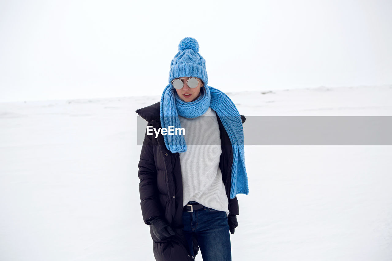 Girl running in a snowy field in a jacket and sunglasses