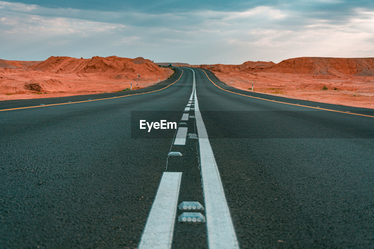 Empty road amidst landscape against sky