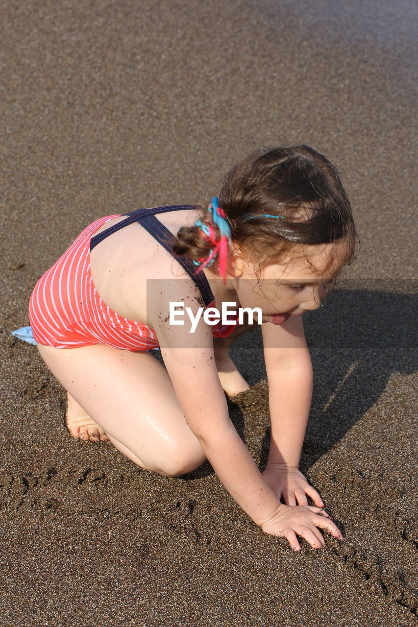 HIGH ANGLE VIEW OF GIRL PLAYING IN SAND