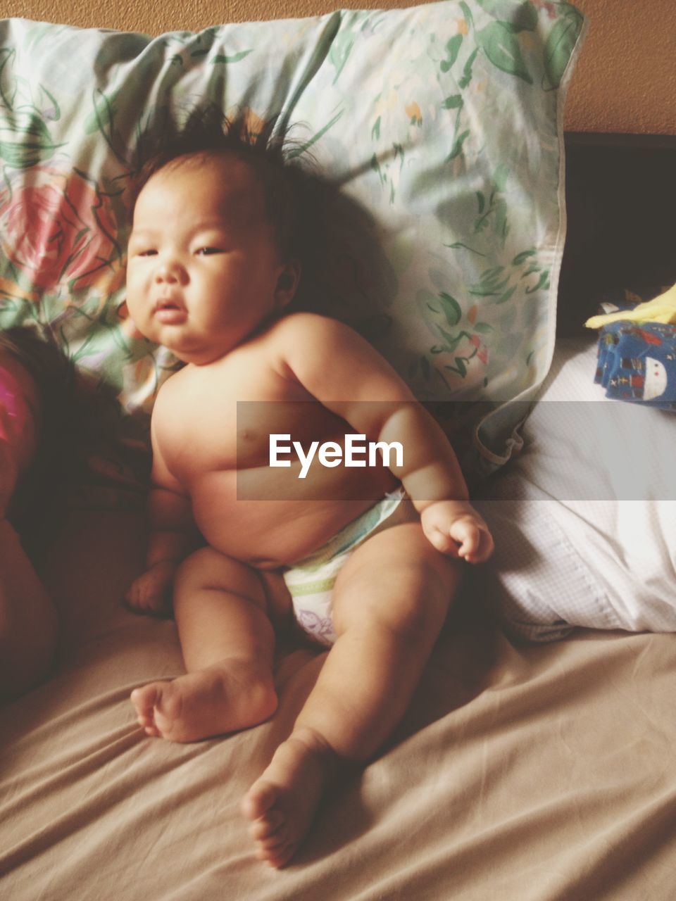 Shirtless baby boy lying on bed at home