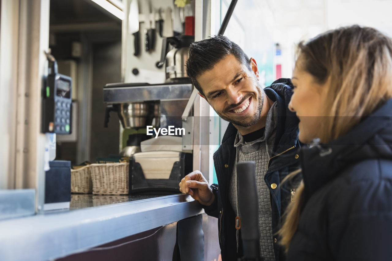 Smiling couple talking with each other at food truck
