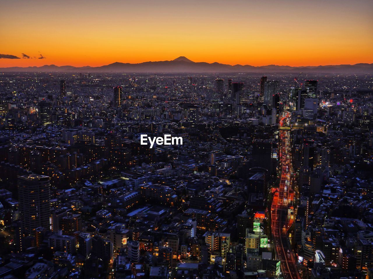 Illuminated cityscape against sky during sunset