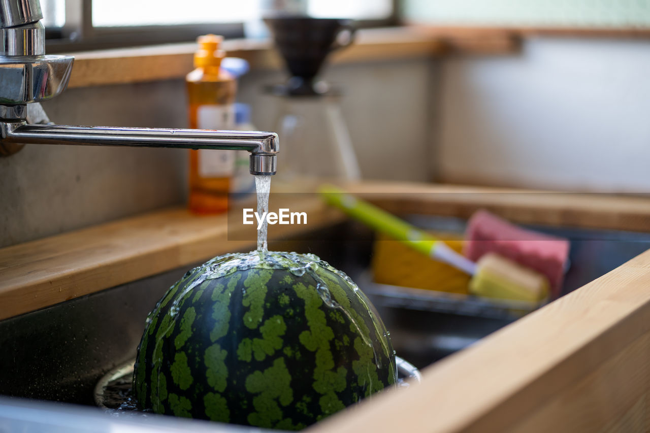 Close-up of fruit under faucet in sink