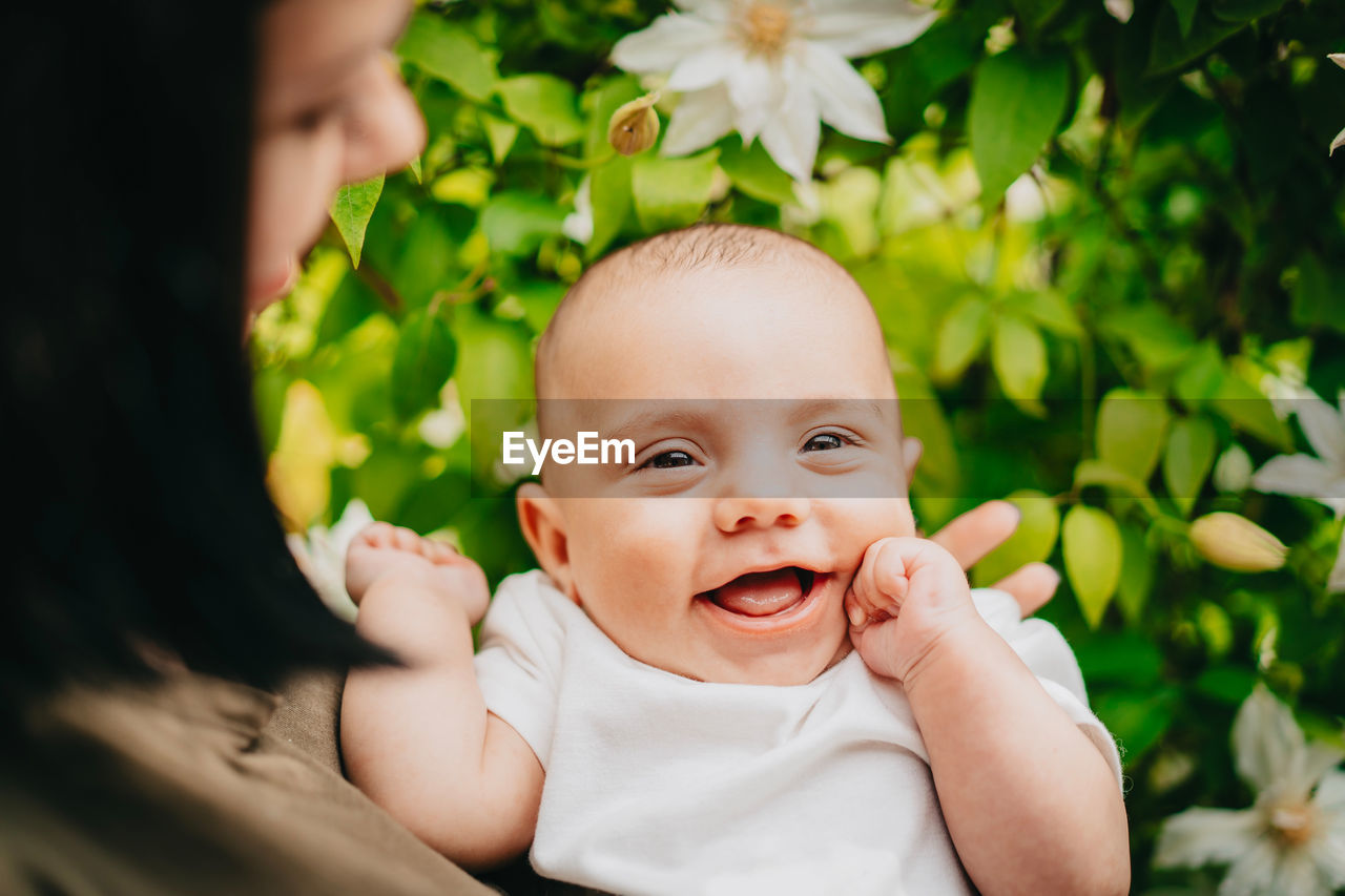 Midsection of mother holding cute baby boy against plants