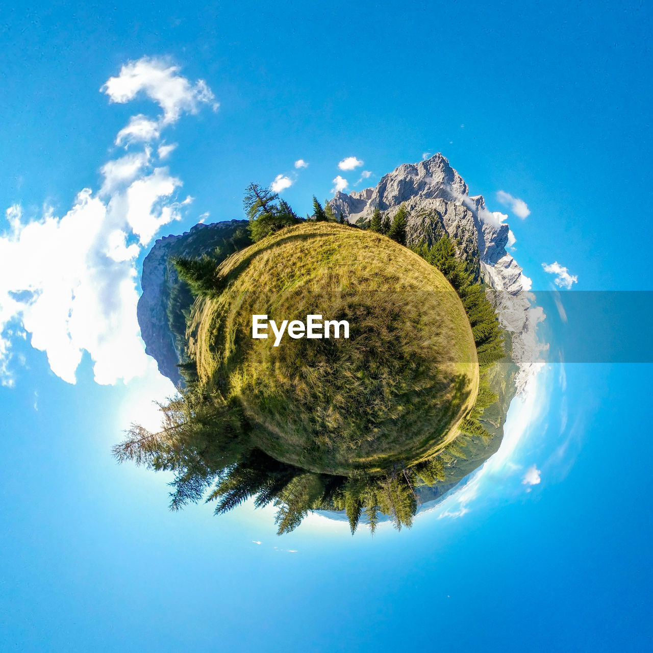 Digital composite tiny planet of mountain landscape against blue sky