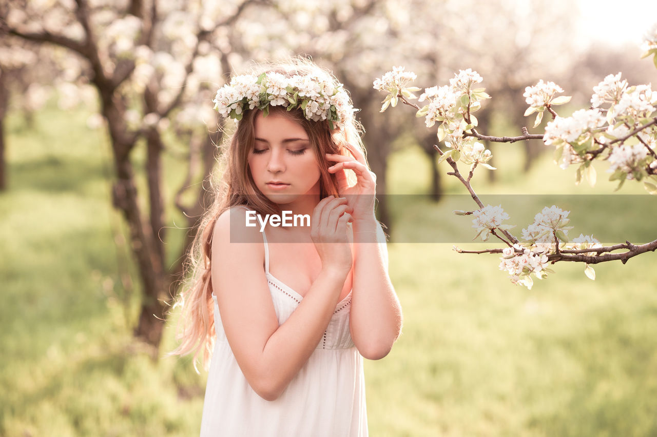 plant, flower, flowering plant, women, one person, nature, spring, young adult, adult, tree, springtime, beauty in nature, female, hairstyle, blossom, fashion, portrait, long hair, bride, freshness, clothing, dress, emotion, outdoors, cherry blossom, headpiece, looking, happiness, sunlight, grass, child, brown hair, summer, fragility, land, field, lifestyles, standing, smiling, waist up, childhood, day, portrait photography, white, pink, focus on foreground, contemplation, wreath, relaxation, copy space, environment, laurel wreath, landscape