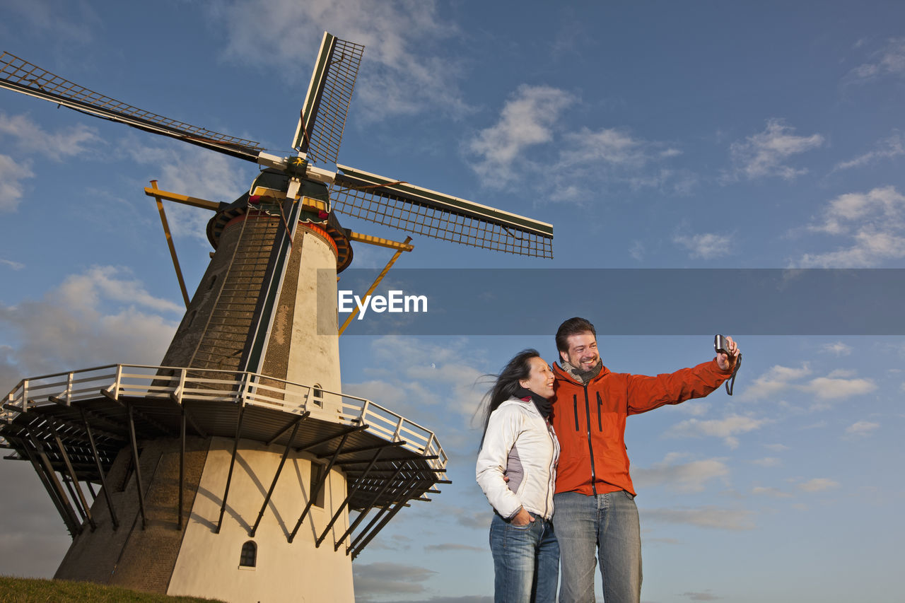 Mature couple taking selfie with windmill in the netherlands