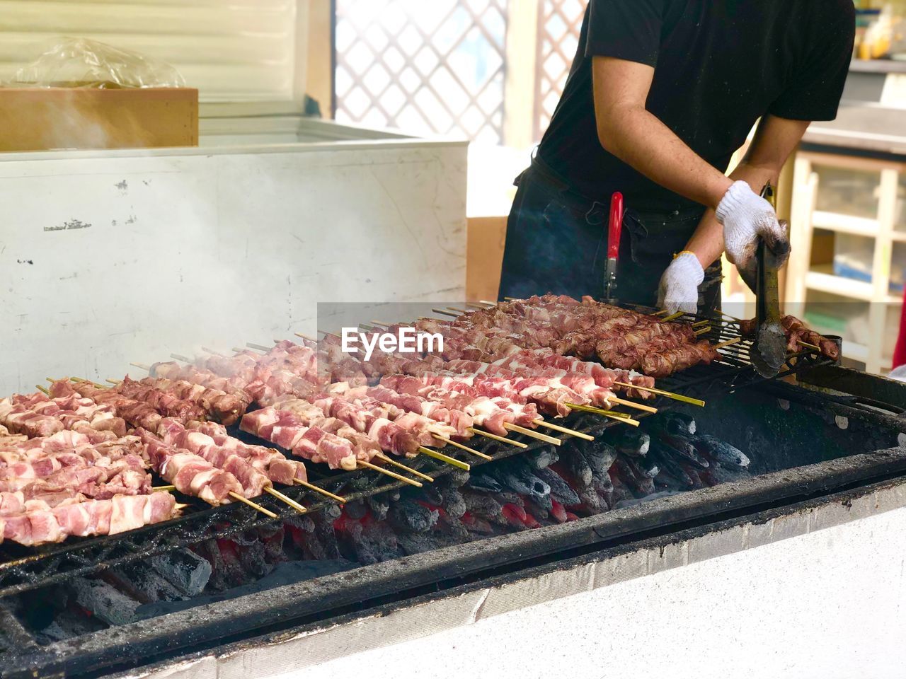 MIDSECTION OF PERSON PREPARING FOOD ON BARBECUE