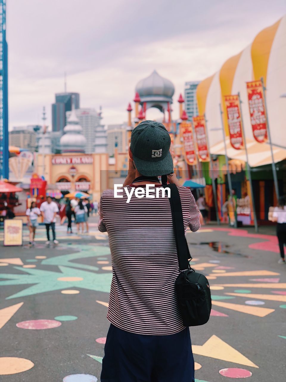 REAR VIEW OF WOMAN STANDING BY MULTI COLORED CITY AGAINST SKY