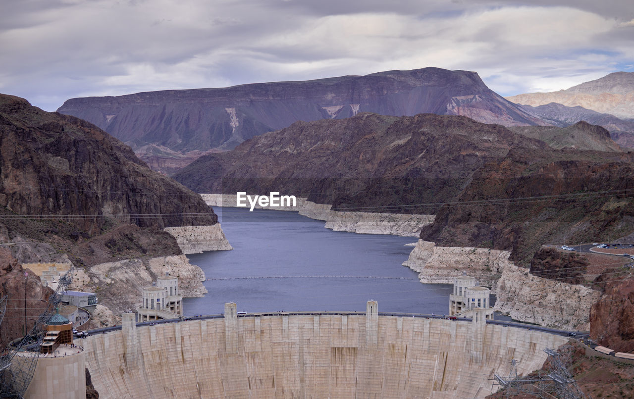 Scenic view of dam and mountains against sky