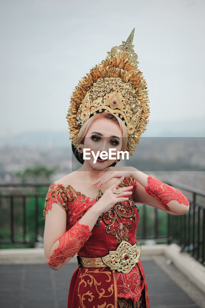 Portrait of smiling young woman custome traditional of bali standing outdoors