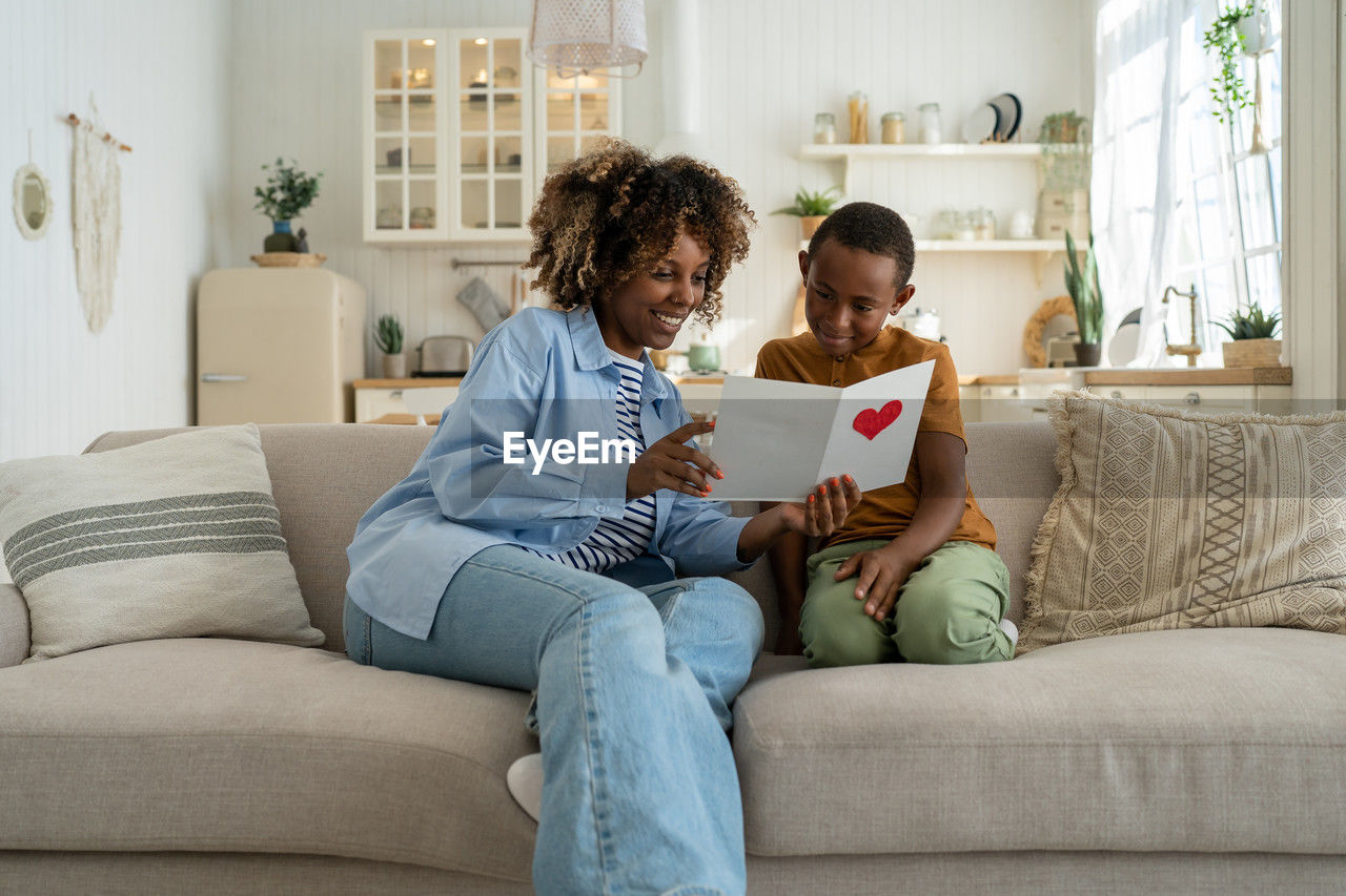 friends using digital tablet while sitting on sofa at home