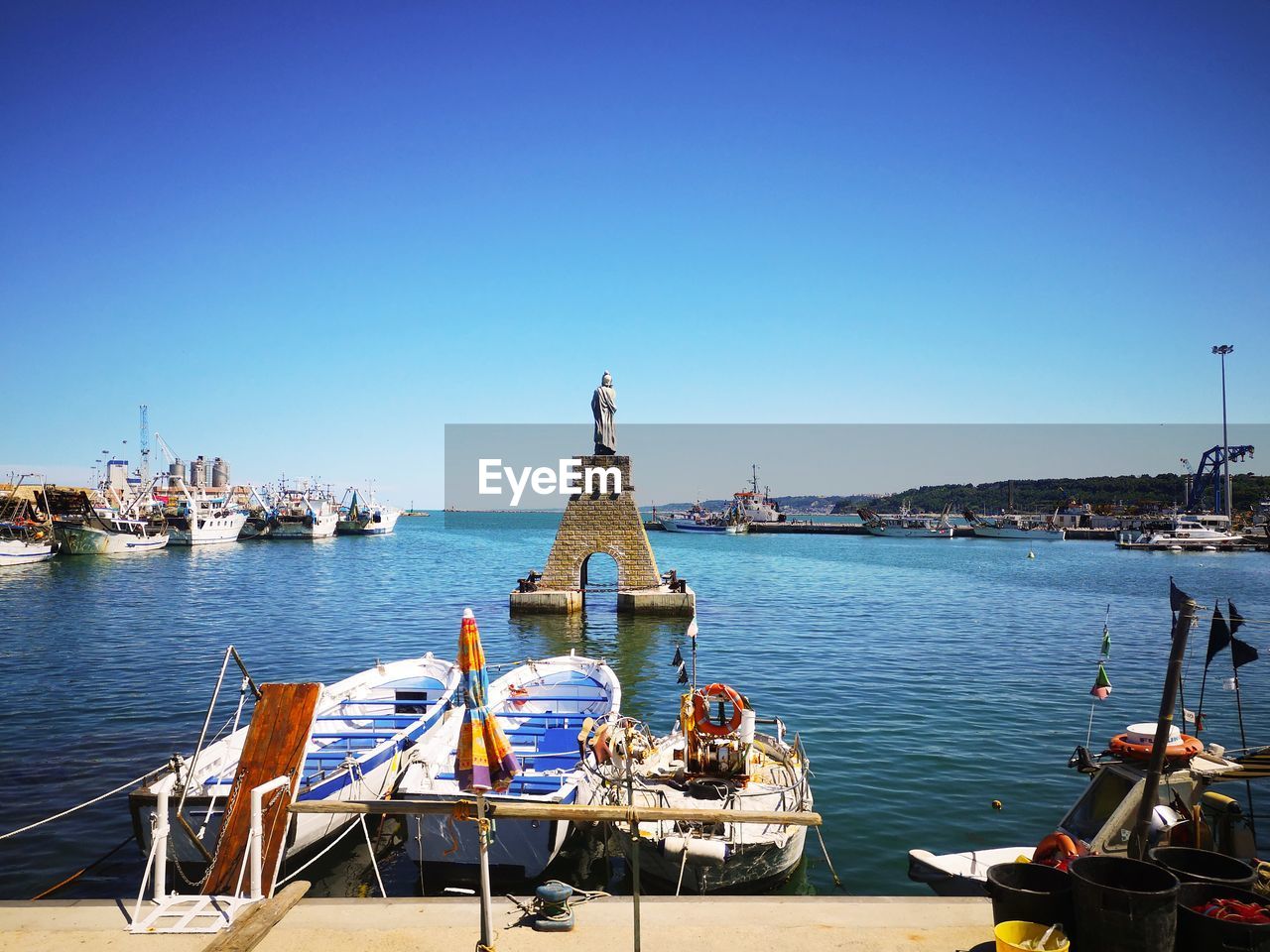 Sailboats moored in sea against clear blue sky