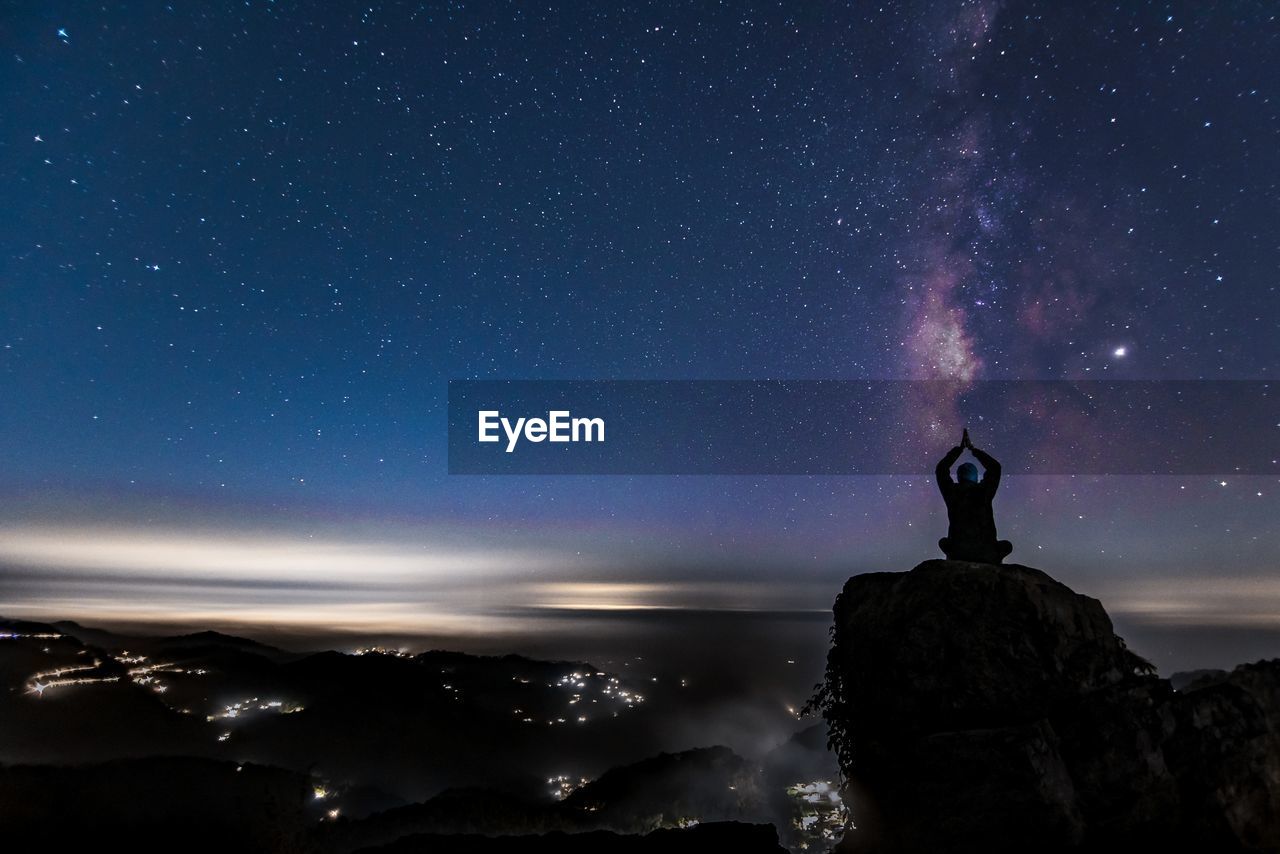 Man standing on rock against sky at night