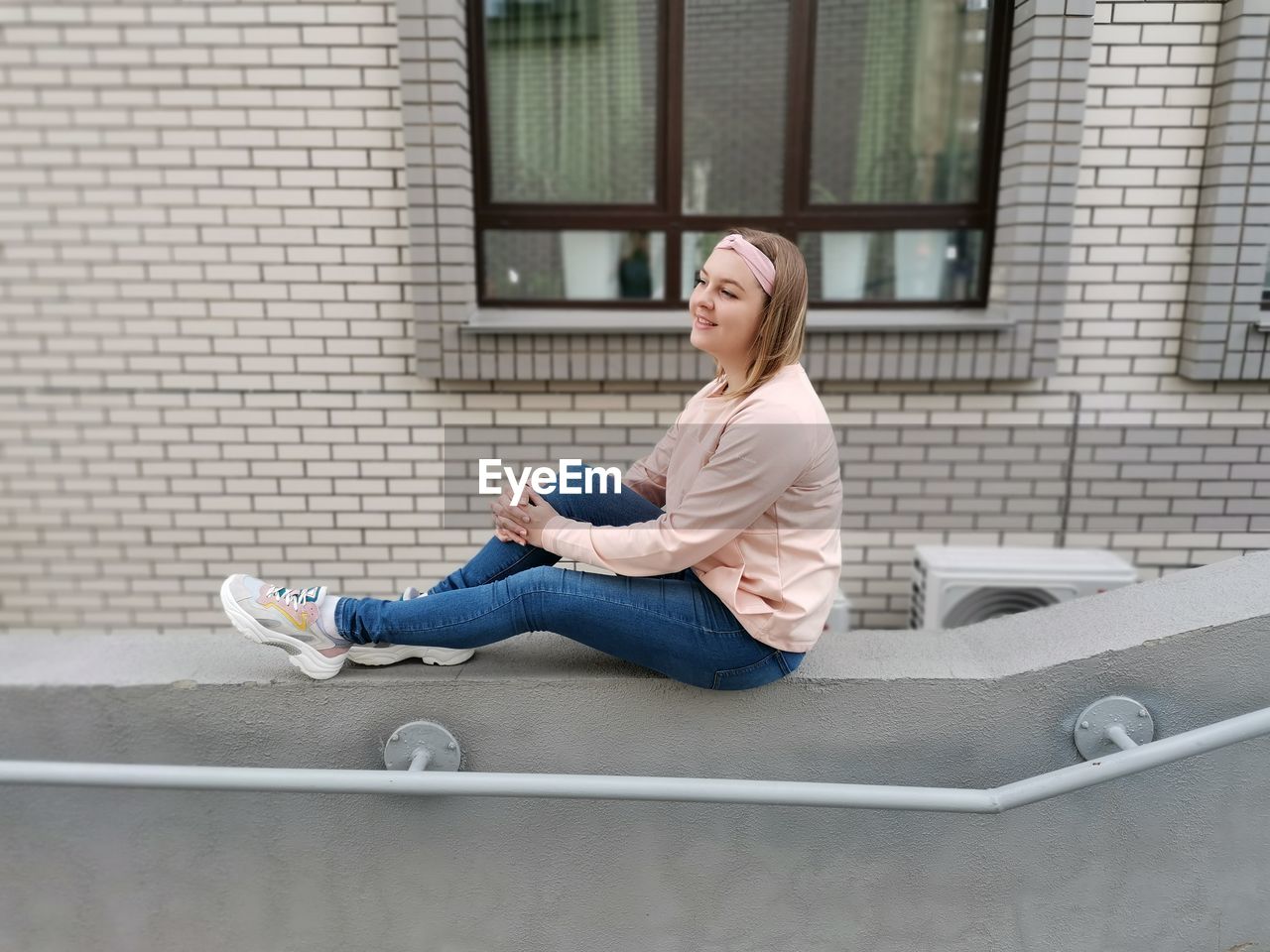 Side view of a young woman sitting on apartment window