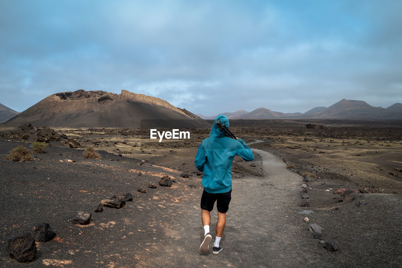 Rear view of man walking on land against sky