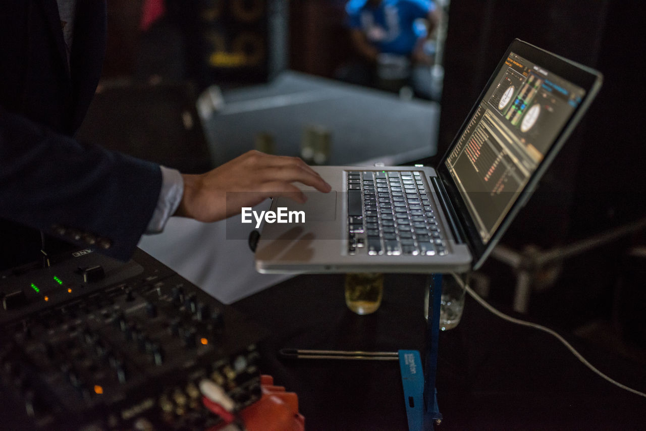 Midsection of man mixing music on laptop