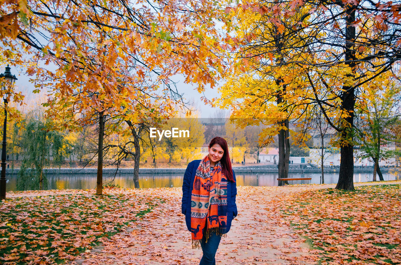 WOMAN STANDING BY PLANTS DURING AUTUMN