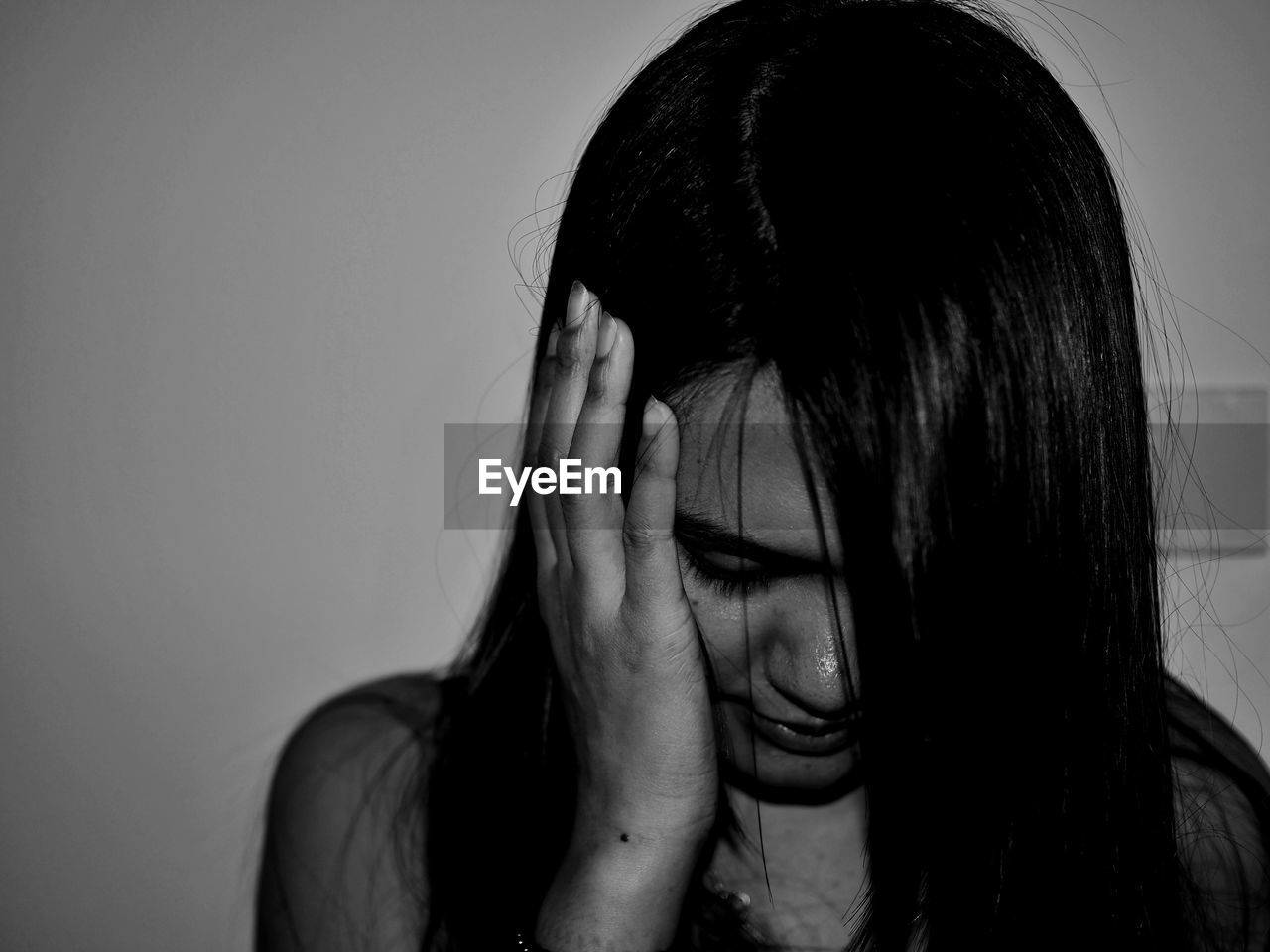 Close-up of woman covering ear against wall