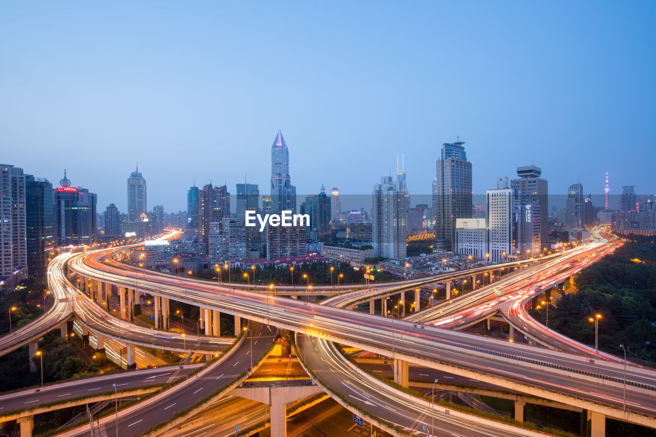 Bridges and modern buildings against clear sky at dusk